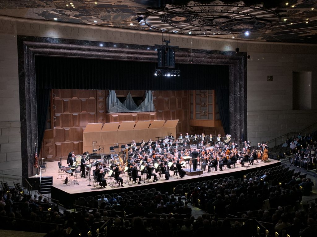 Wide shot of the orchestra and audience in the Forum.